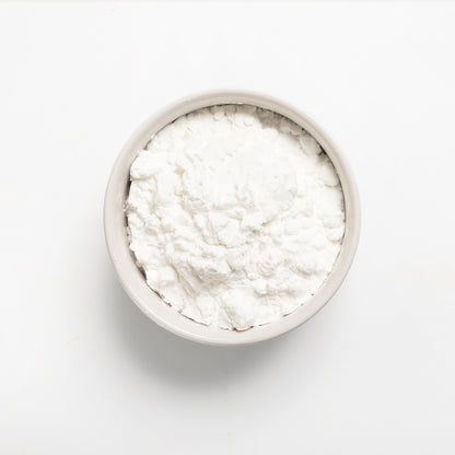A bowl of white potato starch on a white background.