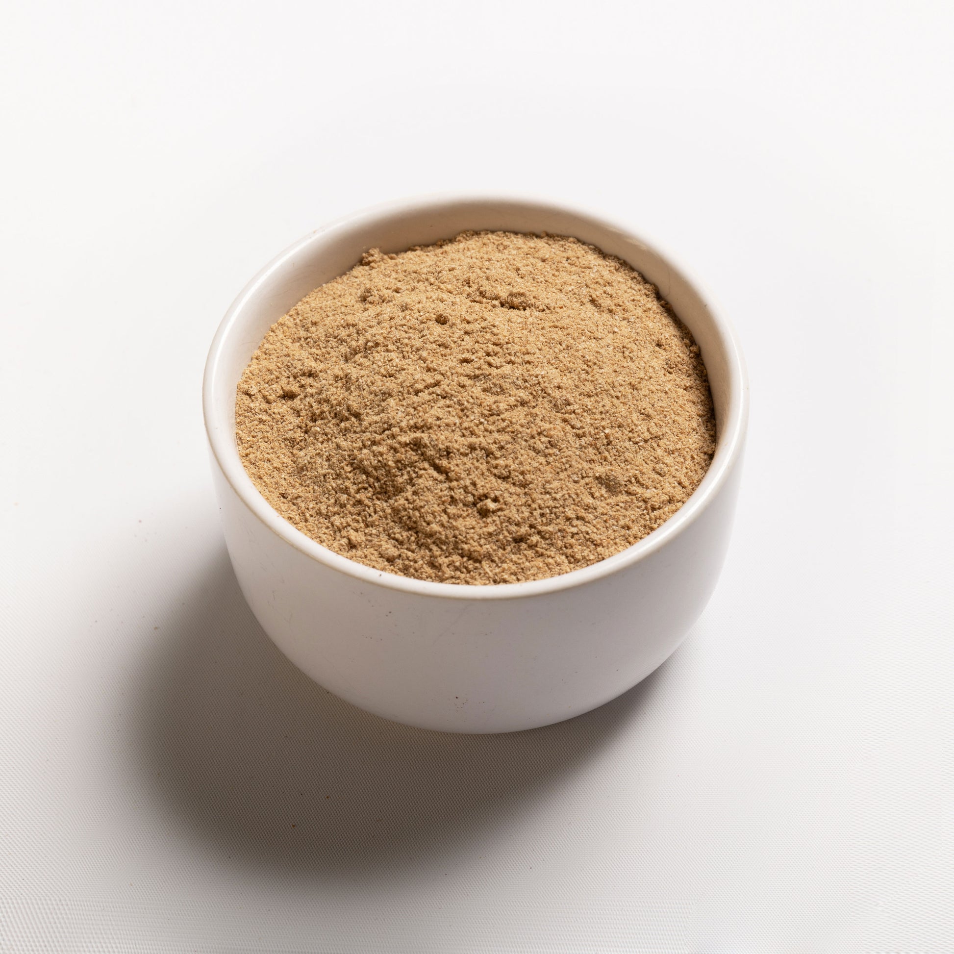 A white bowl filled with psyllium husk powder on a white background.