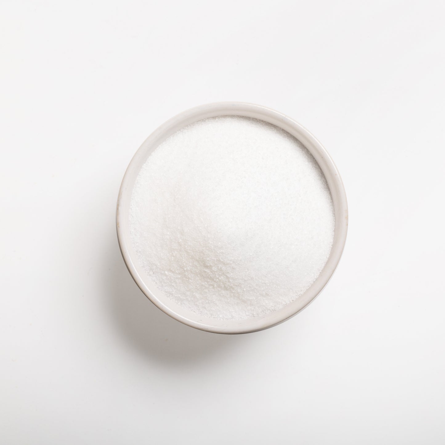 A bowl of purified (untreated) sea salt on a white background.
