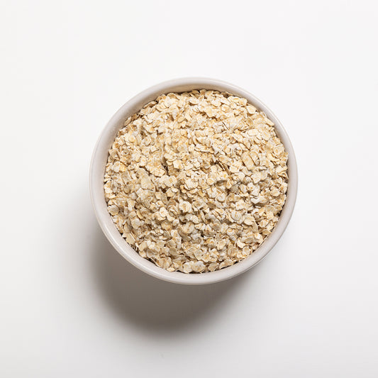 A bowl filled with gluten-free quick rolled oats on a white background.