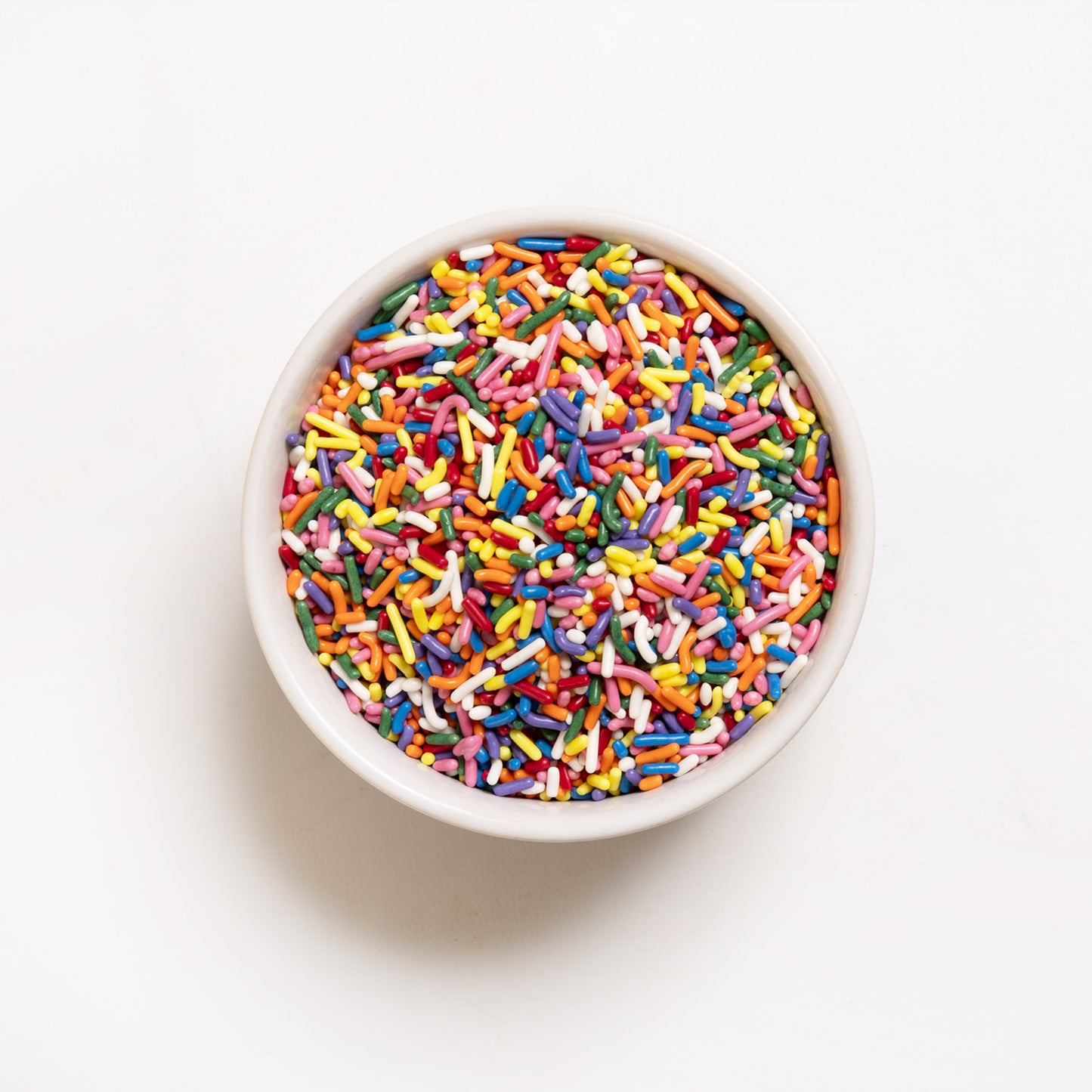 A top view of colorful Rainbow Sprinkles in a white bowl 