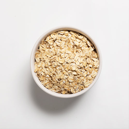 White bowl filled with regular rolled oats on a light gray background