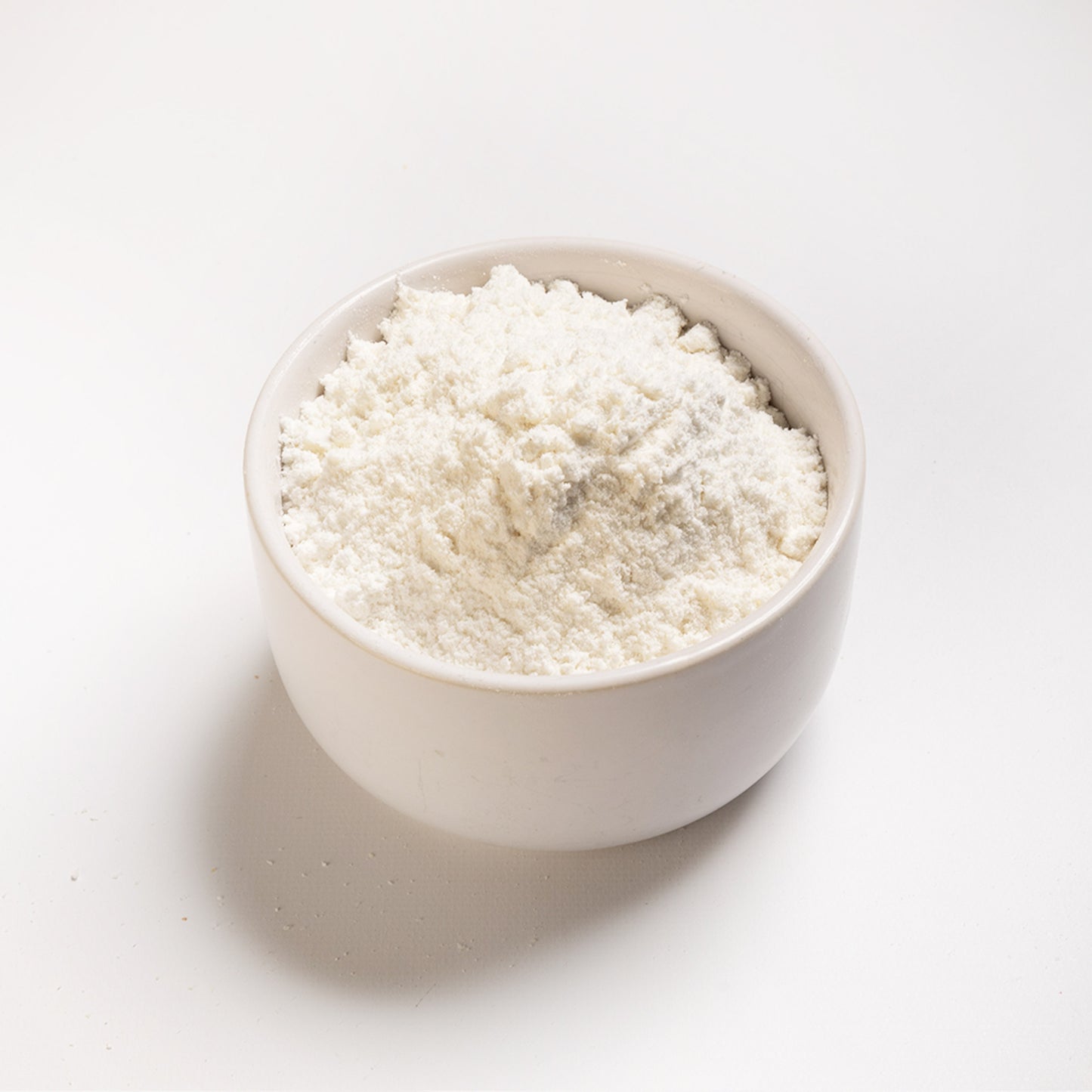 A bowl of snow white corn flour, finely ground, presented on a white background, angle view