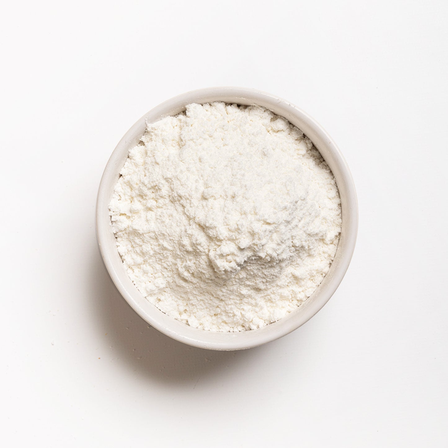 A bowl of snow white corn flour, finely ground, presented on a white background.