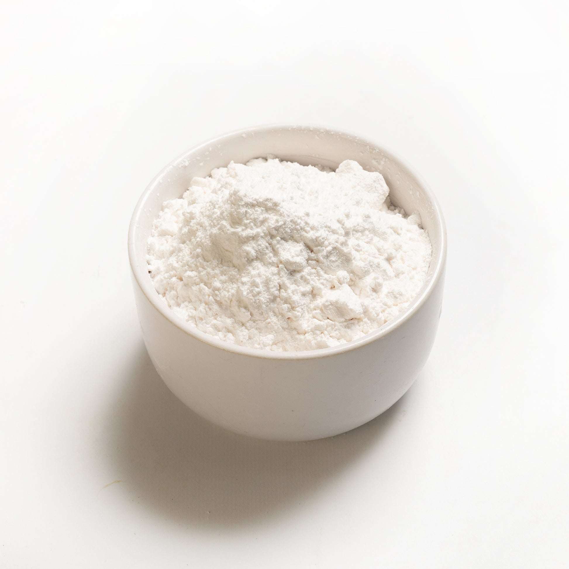 A bowl filled with white tapioca starch on a white background.