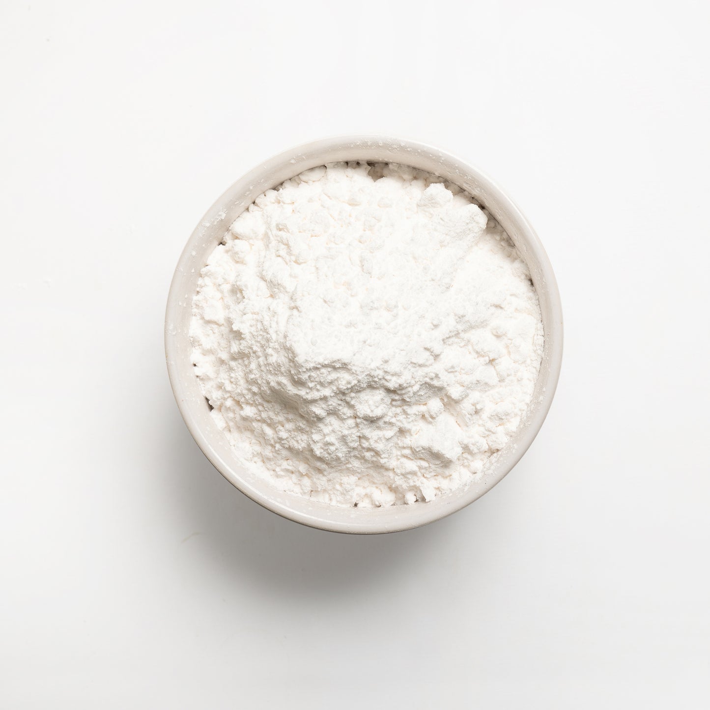 A bowl filled with white tapioca starch on a white background.