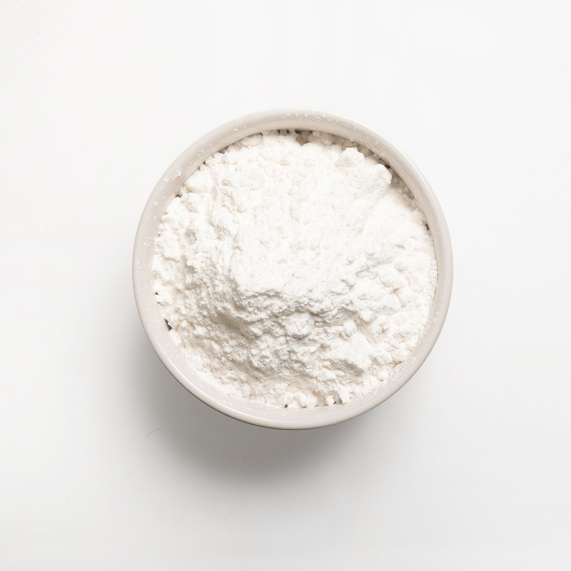 A bowl filled with white tapioca starch on a white background.