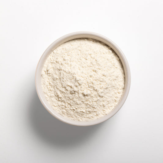 A bowl filled with white flour-like powder on a white background, representing vital wheat gluten.