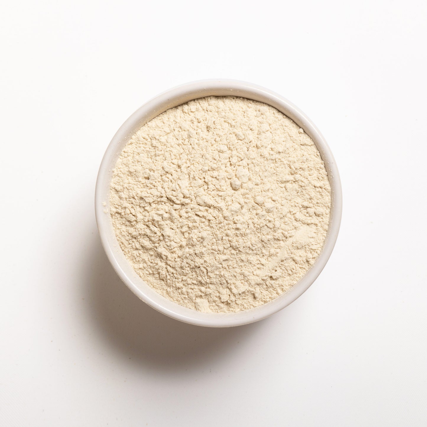 A bowl of unflavored wheat protein isolate powder on a white background.