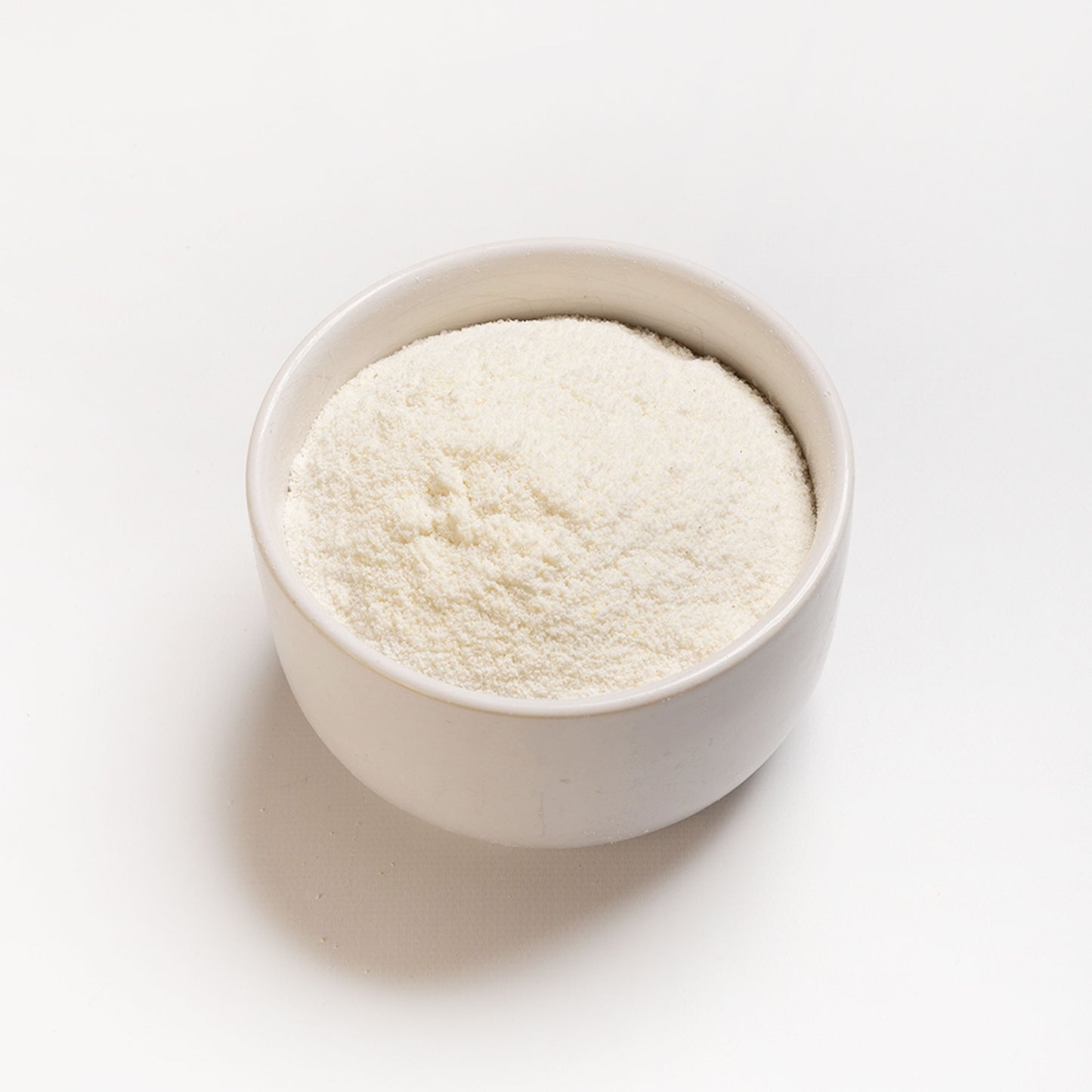 A bowl filled with white arepa flour, which is finely milled cornmeal, angle photo