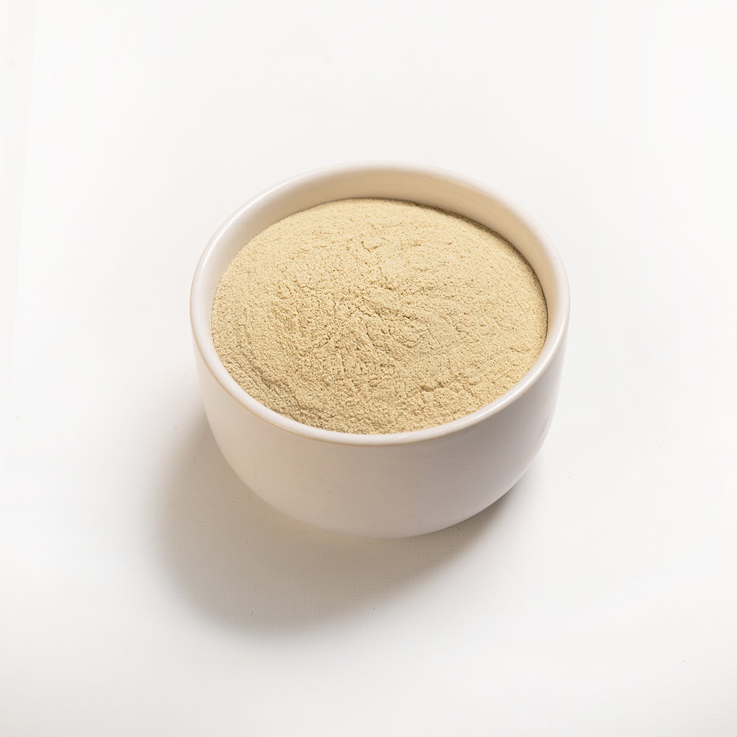 A bowl filled with White Ground Pepper with a white background 