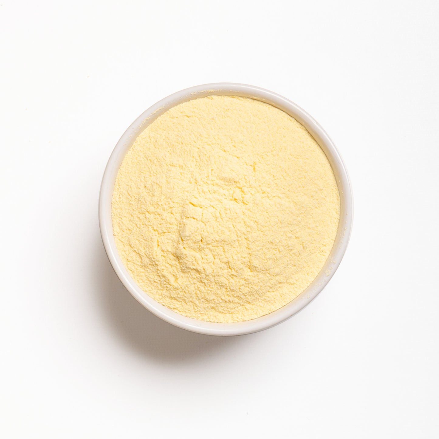 A bowl filled with yellow arepa flour on a white background.