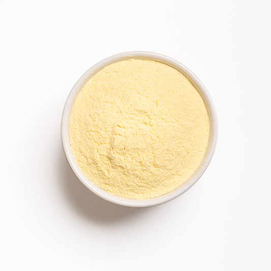 A bowl filled with yellow arepa flour on a white background.