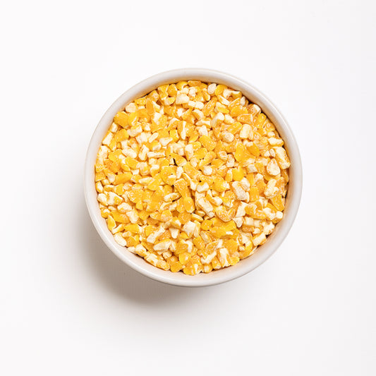 A bowl of yellow flaking grits on a white background, top view