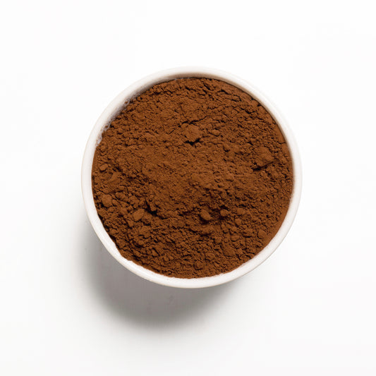 A white bowl filled with Dutch cocoa powder on a white background.