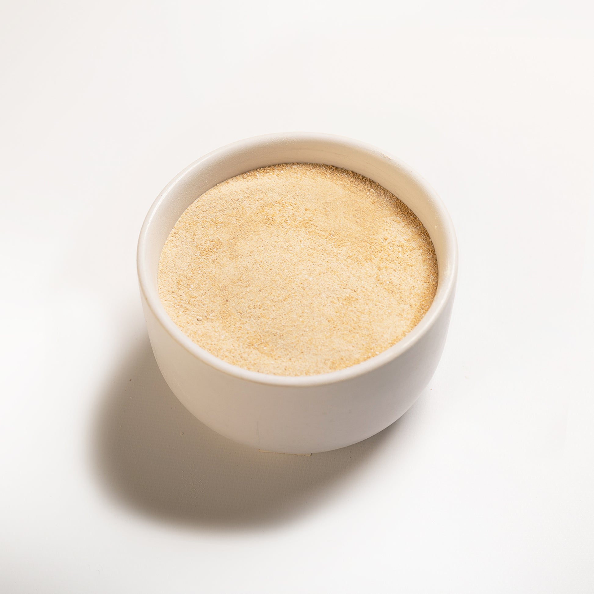 Maple flavor powder in a white bowl at an angle 